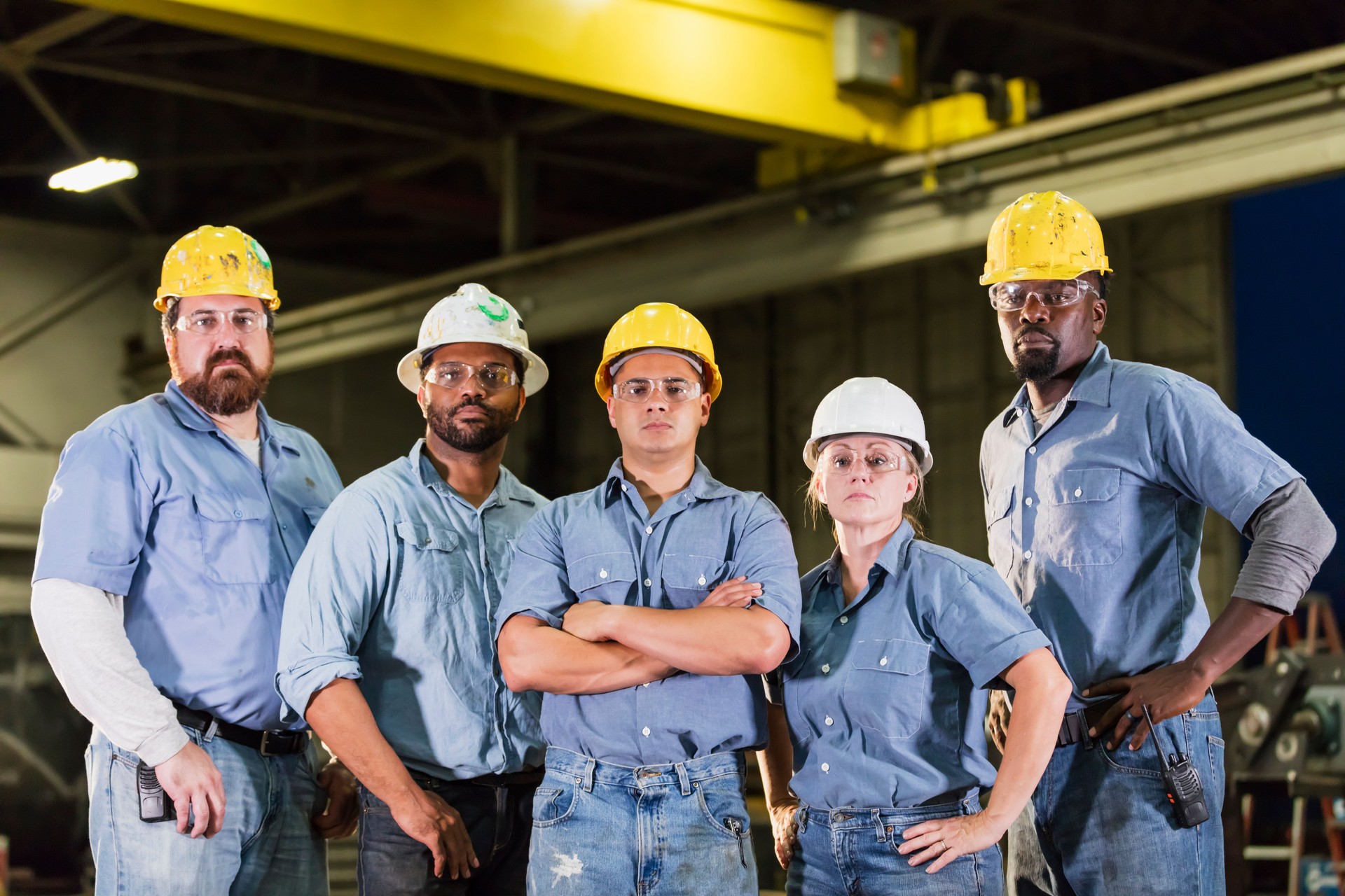 Five workers with hardhats standing in warehouse