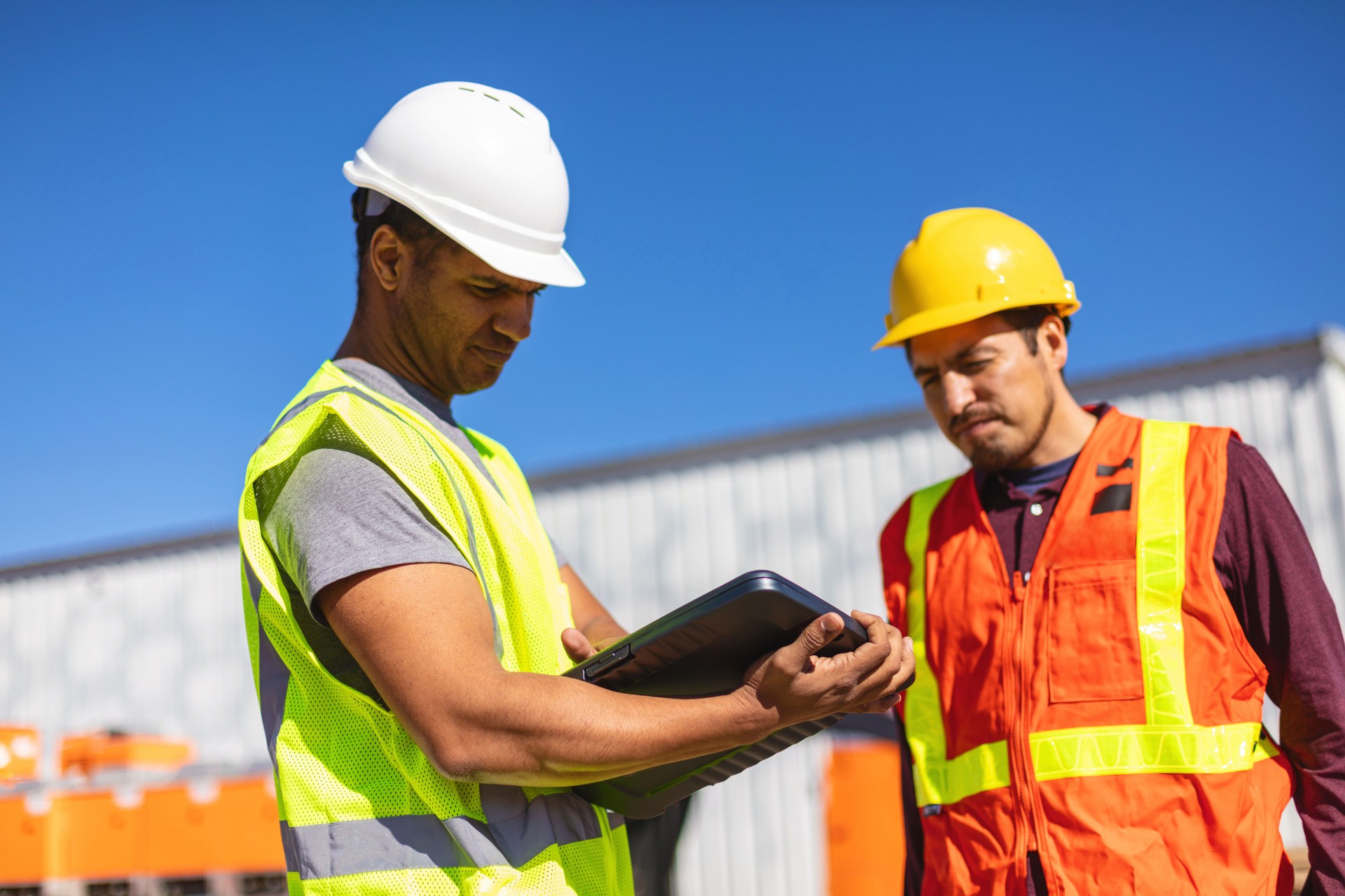 Black and Hispanic Male Construction Workers on Work Site Wearing PPE Evaluating and Discussing Projects Infrastructure Photo Series